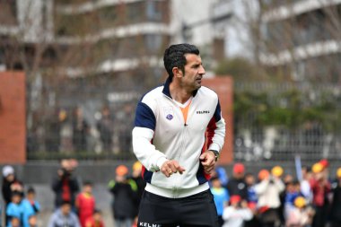 Portuguese former football player Luis Figo plays football with students at an event for the IFDA world legends series - Football Legends Cup - China 2019 in Chengdu city, southwest China's Sichuan province, 22 March 2019. clipart