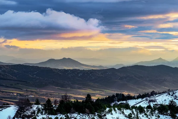 Landscape with mountains, snow and clouds at sunrise.