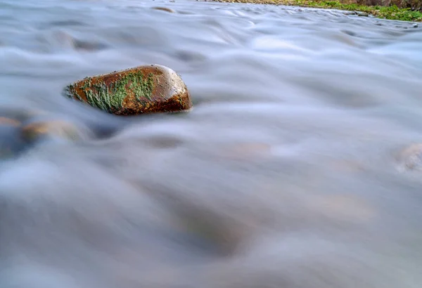 Water rushing down a mossy rock in a river — Stock Photo, Image