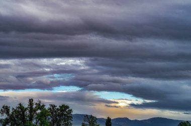 Gün batımında dağlar ve yağmur bulutları ile manzara sahnesi