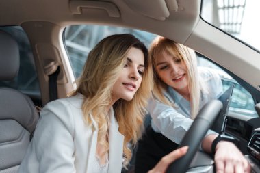 Araba galerisi danışmanı arabanın içini bir müşteriye gösteriyor.