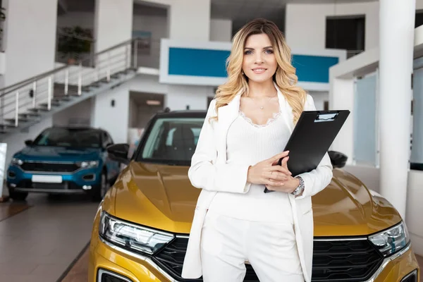 Portrait of saleswoman in car dealership. Business lady is a representative of the car dealership