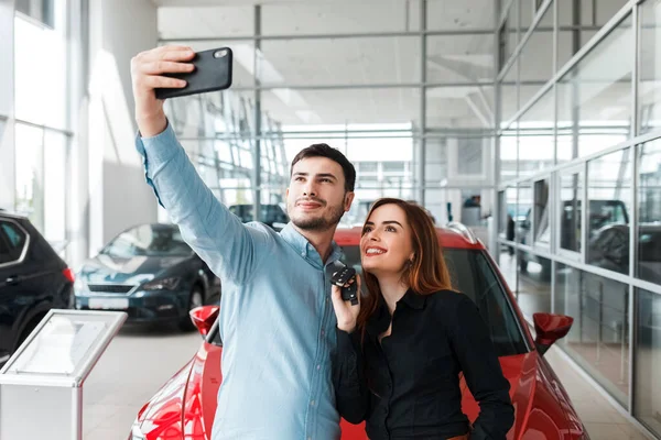 Araba galerisinde selfie çeken bir çift.