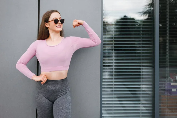 Güneş Gözlüklü Pozitif Atletik Kadın Pazılarını Gösteriyor — Stok fotoğraf