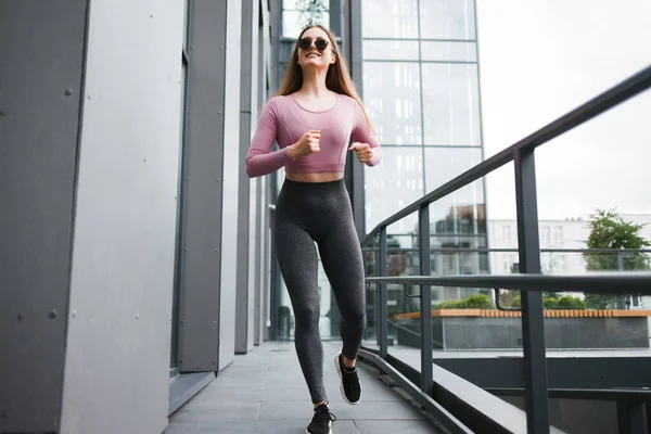 Güzel Bir Spor Kızı Modern Bir Binanın Yanında Koşar — Stok fotoğraf