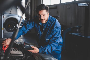 Elektrikli bir cihaz ile oto tamircisi araba aküsünün durumunu kontrol eder