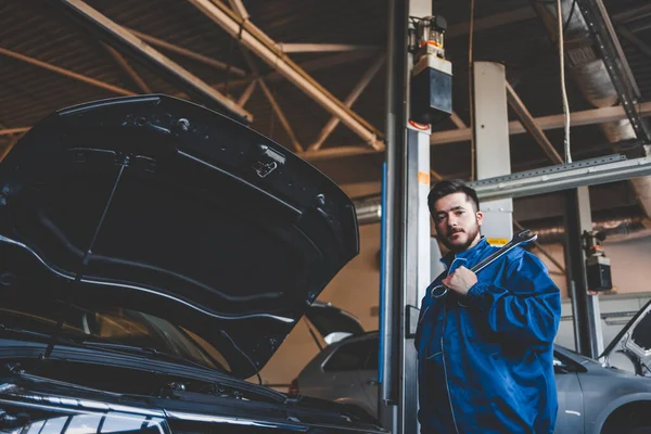 Male Auto Mechanic Standing Car Holding Wrench His Shoulder Vehicle — Stock Photo, Image