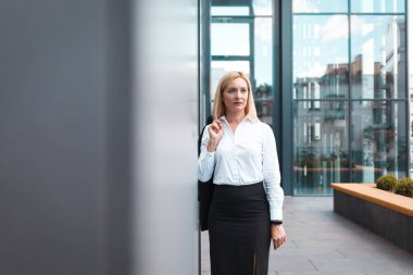 Yorgun kadın ofis çalışanı çok çalıştıktan sonra omuzunda bir ceketle dikiliyor.