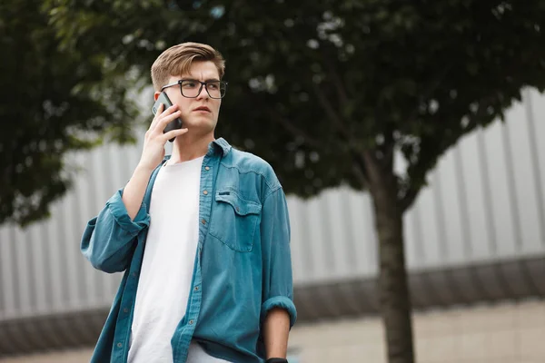 Poważny Młodzieniec Okularach Rozmawiający Przez Smartfona Ulicy — Zdjęcie stockowe