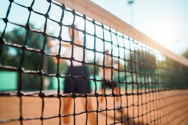 Genç çift tenis oynuyor, kalede seçici bir odak noktası var.