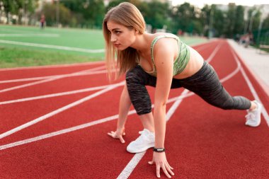 Atletik kız koşmaya hazırlanıyor.