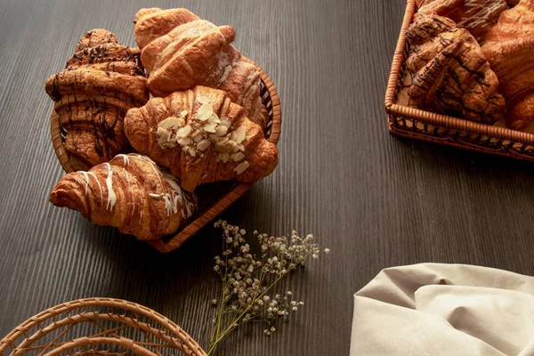 Mandulával, csokoládéval és porcukorral ellátott croissant egy fából készült, sötét asztal Vértes — Stock Fotó