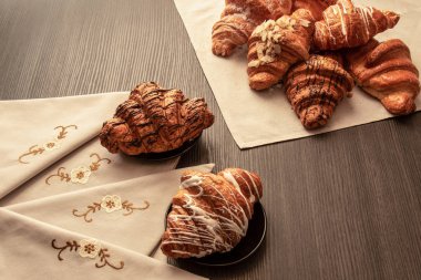 peçete ve masa örtüsü ile bir masada badem, çikolata ve pudra şekeri ile pişmiş kruvasan, closeup