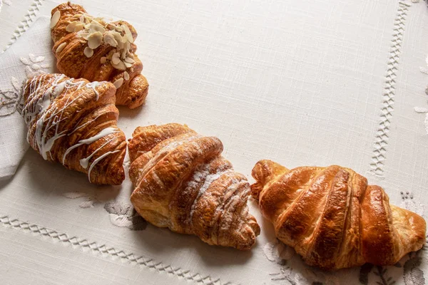 Croissants frescos com amêndoas, açúcar em pó em uma mesa com guardanapos e toalha de mesa, close-up, vista superior — Fotografia de Stock