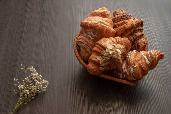 Freshly baked croissants with almonds, chocolate and powdered sugar  on a wooden dark table top view — Stock Photo, Image