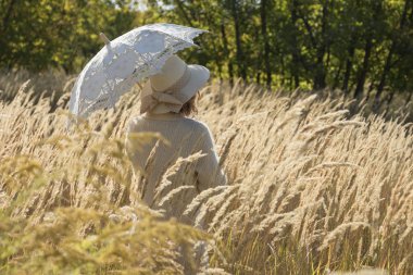 gün batımında bir şemsiye ile yüksek çim arasında kırsal üzgün yalnız kız