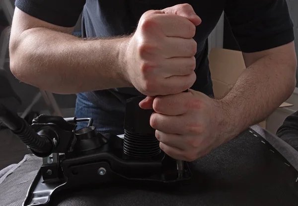 Adam bir sandalyeyi tamir ediyor. Erkeklerin elinde bir tornavida. Montaj ve onarım kavramı