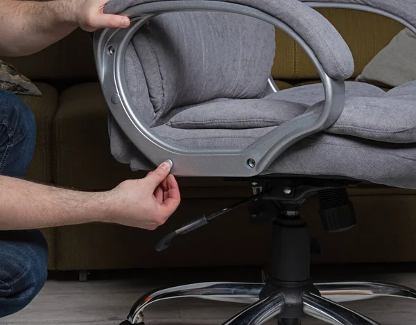 Evde erkekler tarafından tekerlekli sandalyenin tamir ve montajı. Sandalyede gri kumaş