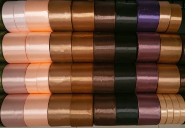 Mağazadaki bir rafta parlak ipek kurdeleler. Ev yapımı konsept. Kumaş mağazasında ve nakış dükkanında çok renkli kurdeleler..