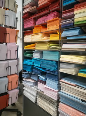 Mağazalardaki raflarda farklı renk ve boylarda zarflar var. Kırtasiye ve sanat atölyesi. Zarflar ve kağıtlar sıralandı. Renk arkaplanı