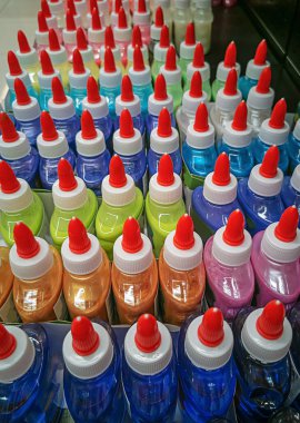 Ofis malzemeleri dükkanında dekoratif renk yapıştırıcısı olan şişeler. Rafta kırmızı kapaklı parlak bir yapıştırıcı..