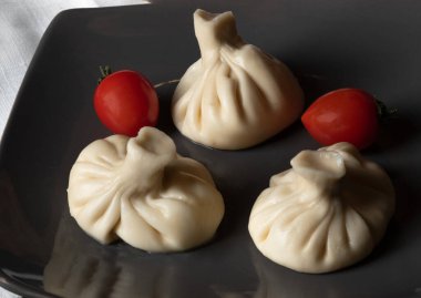 Khinkali, domatesli, siyah bir tabakta. Bir tabak Gürcü mutfağı. Üst görünüm