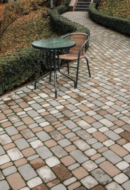 Sonbahar parkında tuğla yolda yuvarlak masa ve sandalye.