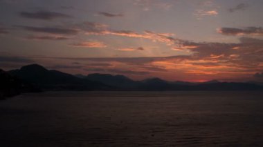 Zaman atlamalı. Sahil üzerinde şafak. İtalya, Salerno. Güneş dağlardan doğar. 4k.