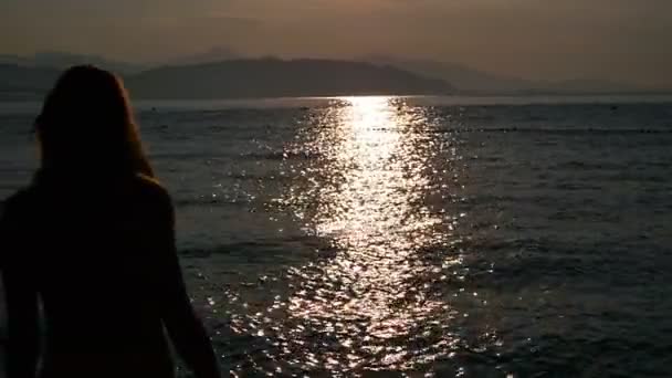 Bir siyah mayo güzel kız deniz güneş doğarken girer. Deniz ve plaj ile mutlu. Suya gider. — Stok video