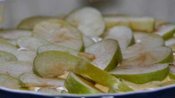 Close-up. Vrouw maken appeltaart. Cook zet apple plakjes in de pan bakken. Gesneden appels op cake beslag in de pan bakken. — Stockvideo