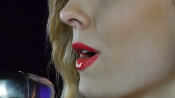 Close-up da cara do cantor com microfone em um fundo fumegante preto. Cantora canta uma canção no palco no escuro — Vídeo de Stock