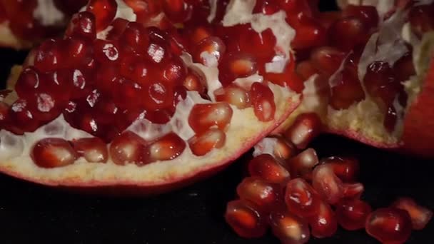 Deel van vers gemaakte granaatappel. Verse rode granaatappel zaden geïsoleerd op een zwarte achtergrond. Close-up. — Stockvideo