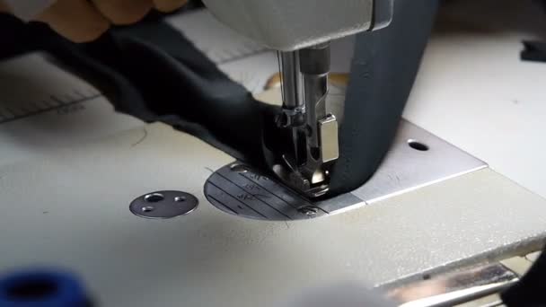 Primer plano del sastre. Las manos femeninas de una costurera en el trabajo. Cortar el hilo y coser con una máquina de coser con material negro. Vídeo en cámara lenta . — Vídeo de stock