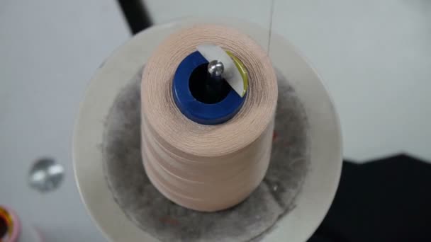 Kledingstuk fabriek. Spoel van hoge kwaliteit katoen naaigaren, close-up. Beige draad. Voor alle doeleinden draad spools op een naaimachine spindel. — Stockvideo