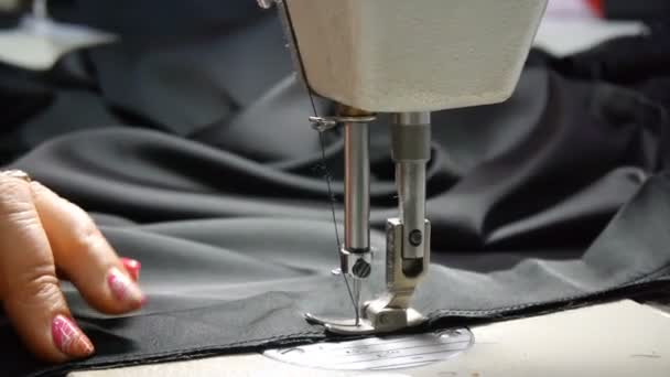 Primo piano del sarto. Mani femminili di una sarta a lavoro. Cucito con una macchina da cucire con materiale nero. Industria della moda . — Video Stock