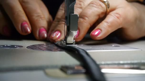 Primer plano del sastre. Las manos femeninas de una costurera en el trabajo. Costura con una máquina de coser con material negro. Industria de la moda . — Vídeos de Stock