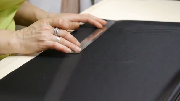 Female hands of a seamstress at work. A dressmaker cutting a high quality fabric black, before you sew it and make a piece of high fashion clothing. Traditional concept, industry and fashion. — Stock Video