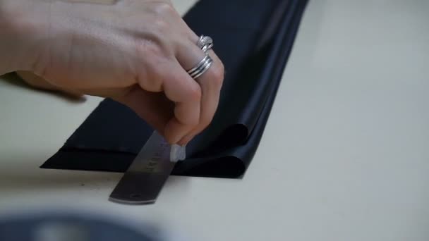 A dressmaker cutting a high quality fabric black, before you sew it and make a piece of high fashion clothing. Close-up. — Stock Video