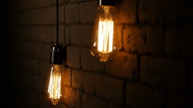 Vintage filament Edison ampul. Lambalar karanlıkta yanar. Bir tungsten filament ile akkor lamba titriyor. Işık yanıp söner. Yakın çekim.