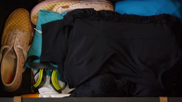 Womens hands are packing a suitcase for travel. Top view. Towel and other stuff. The girl is preparing to fly to the resort. Travel concept. — ストック動画