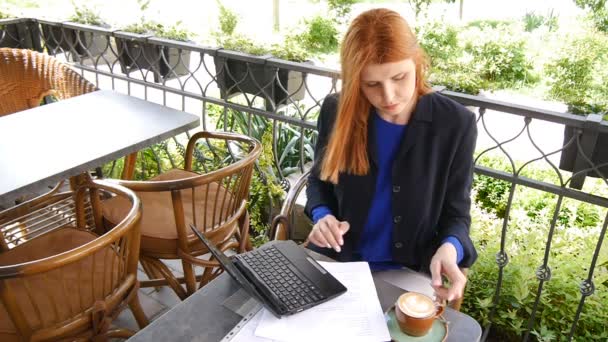 Jovem mulher de negócios atraente trabalhando com documentos e laptop no café, bebendo café . — Vídeo de Stock