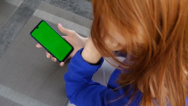 Κορίτσι με κόκκινα μαλλιά χρησιμοποιώντας το κινητό τηλέφωνο με πράσινη οθόνη. Κοντινό. — Αρχείο Βίντεο