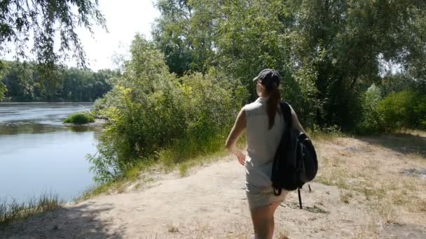 Girl tourist backpacker travel. Woman looking at river flowing thinking about life. Girl relaxing in nature enjoying peace and calm landscape nature. — Stock Video