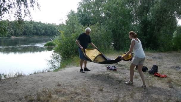 Father and daughter putting up tent, preparing to overnight in wild, green tourism, hiking. Happy travels concept. — Stock Video