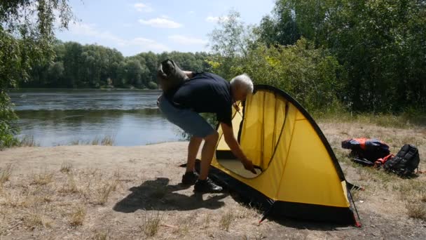 Homem idoso aposentado turista colocar um saco de dormir na tenda. Turismo verde, caminhadas . — Vídeo de Stock
