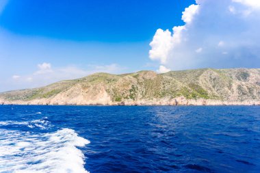 deniz, kayalar ve mavi bulutlu gökyüzü ısmarlayarak