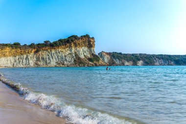 mavi deniz suyu ve kayalık kayalıklar, insanlar suda yüzmek 