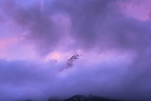 purple sky, hill top covered in clouds