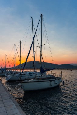 Gün batımı gökyüzü altında limanda Demirli tekneler