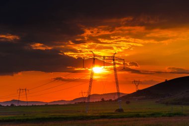 Elektrik kuleleri ve tepeler ile dramatik günbatımı gökyüzü